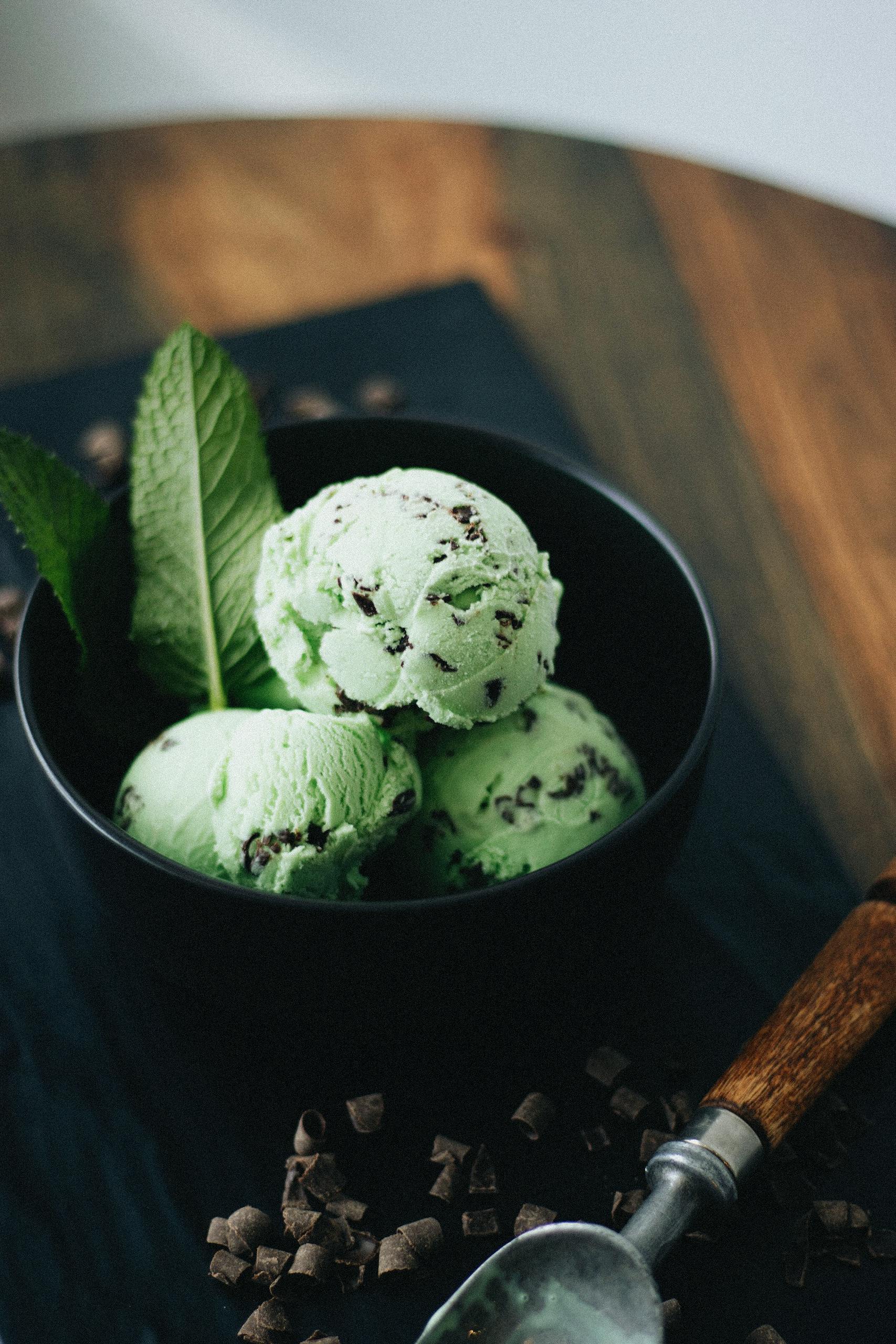 Artisan mint chocolate chip ice cream with fresh mint leaves, perfect for dessert photography.