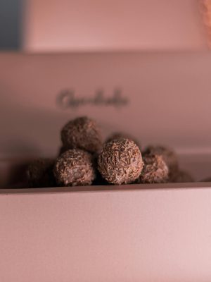 Close-up of decadent chocolate truffles in a soft pink box, perfect for gifting.