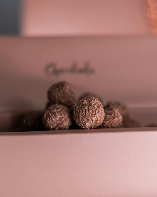 Close-up of decadent chocolate truffles in a soft pink box, perfect for gifting.