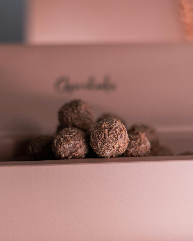 Close-up of decadent chocolate truffles in a soft pink box, perfect for gifting.