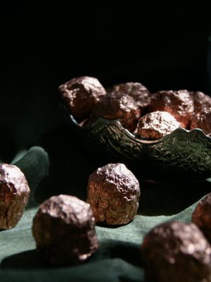 Luxurious dark chocolate truffles elegantly wrapped in foil, presented in a decorative bowl.